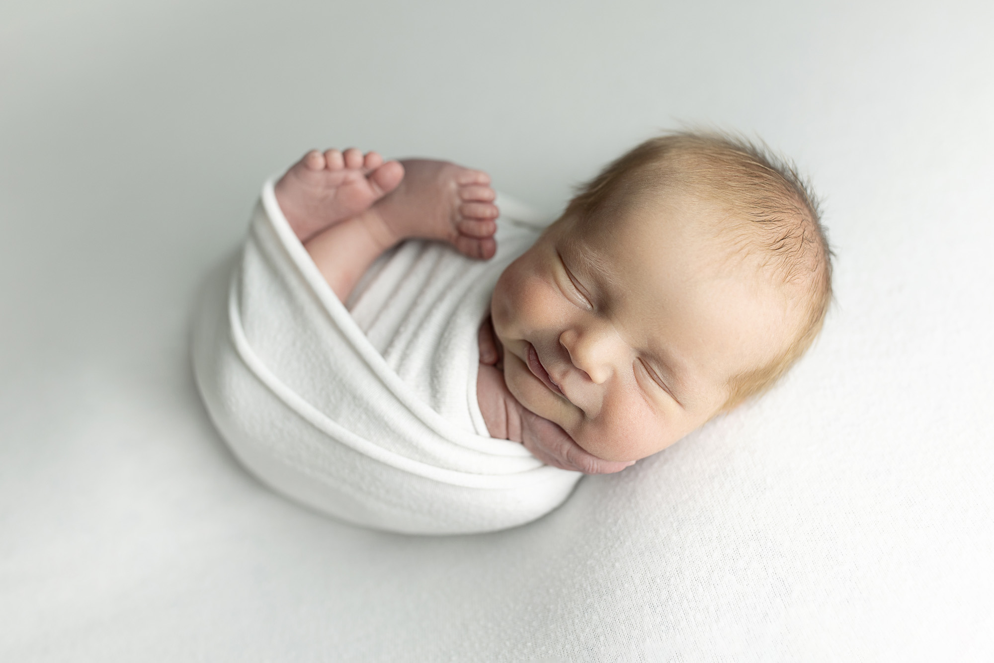 Salt Lake City newborn photographer studio portrait of wrapped baby on neutral background in Bluffdale Utah